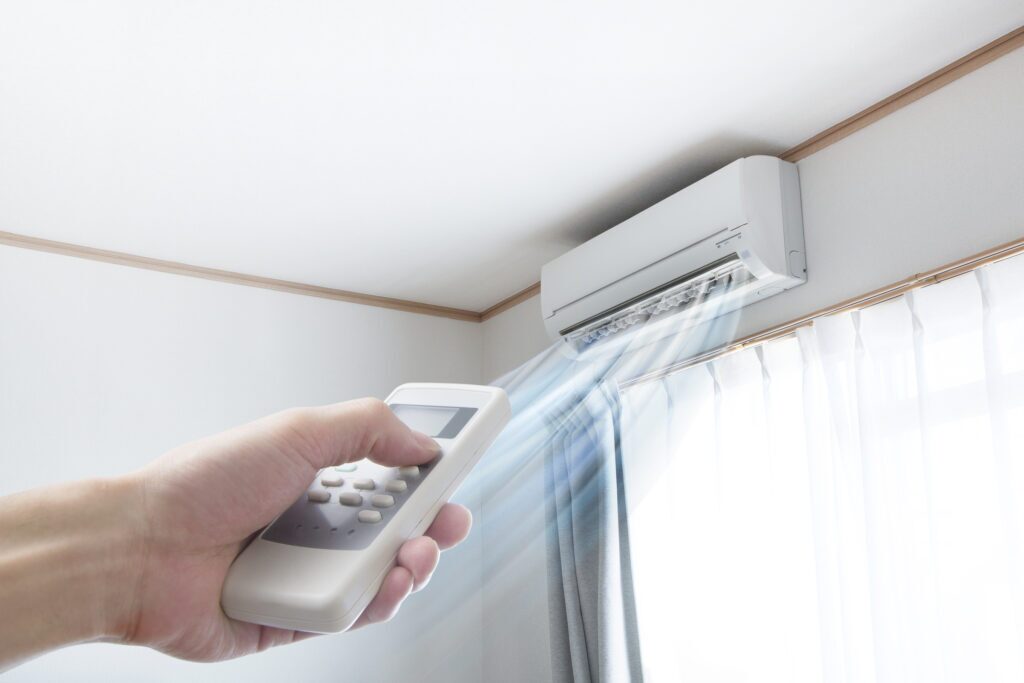 Woman's hand pointing a remote at a ductless AC unit